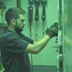 a man wearing gloves and working on a boiler controller
