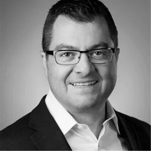 A man in a suit and glasses, representing a Water Treatment Supplier, smiles at the camera against a plain, light background. The image is black and white.