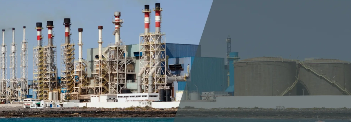 A large industrial desalination plant with multiple smokestacks stands by the sea. The left side is clear and colorful, while the right side is dimmed with a grey overlay. Several boats are visible on the water.