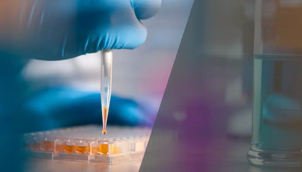 A gloved hand uses a pipette to transfer a liquid into a well plate in a laboratory setting, with scientific glassware blurred in the background.